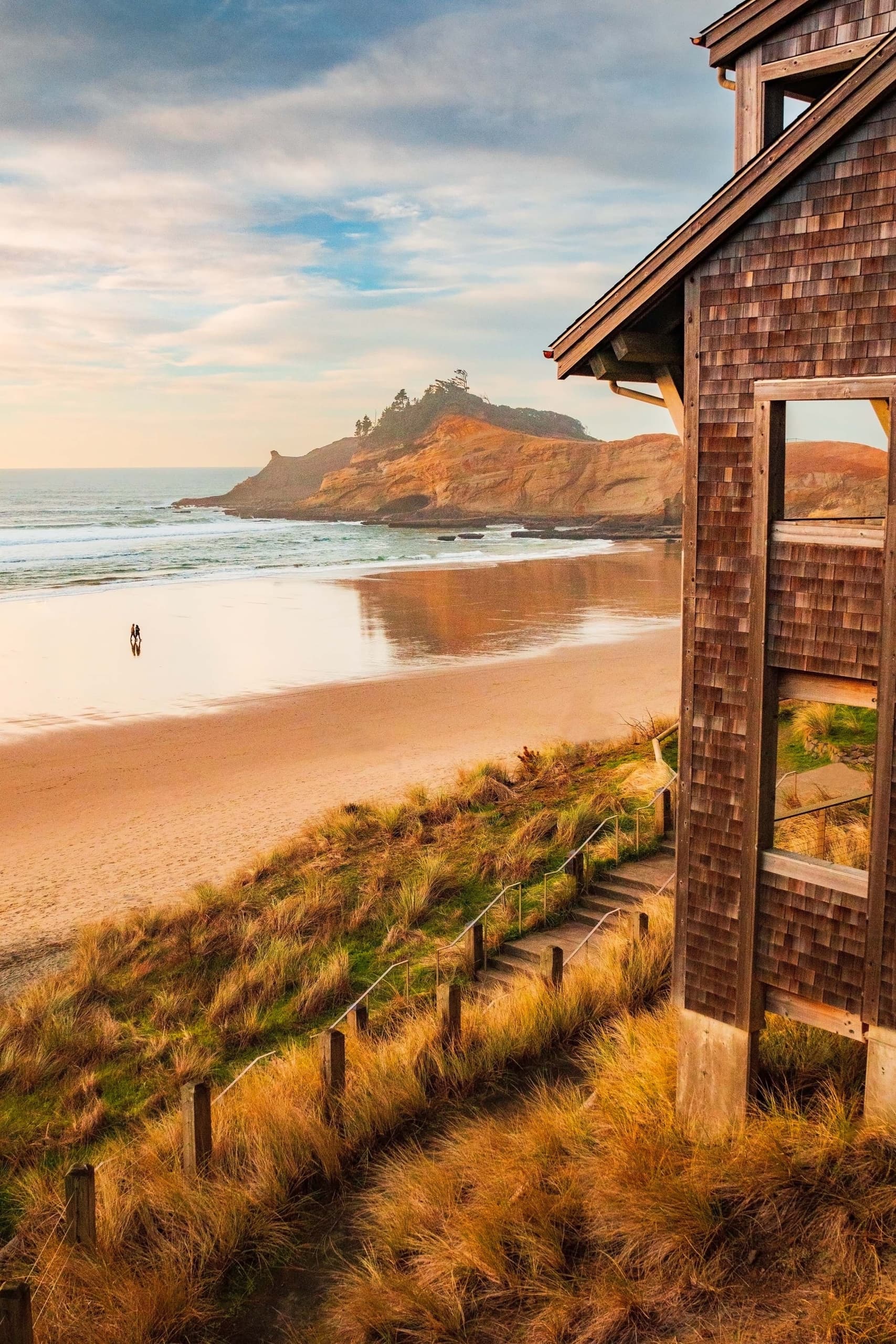 A view of the beach and a couple walking on it with a beautiful blue sky at Headlands