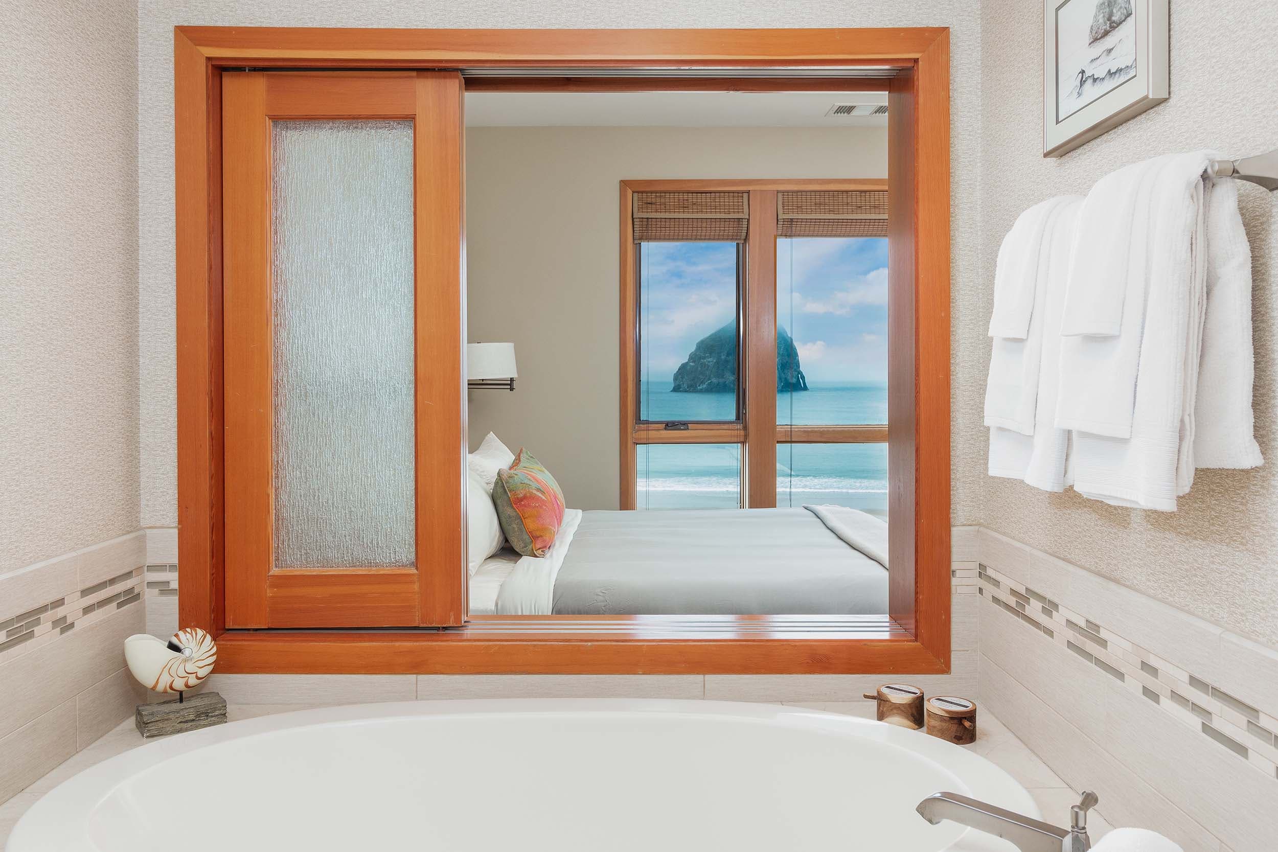 A soaker tub with a view of the ocean and haystack rock in a 2 bedroom cottage at Headlands