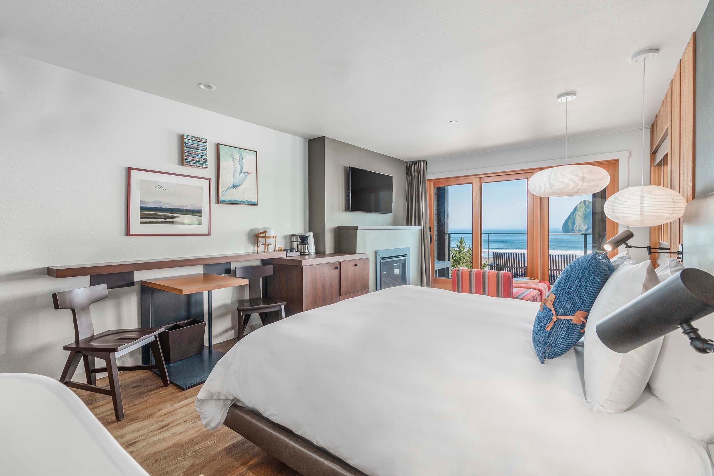 a bed, desk, and lounge area in a King Signature room in the Oceanfront lodge at Headlands with a view of Haystack rock