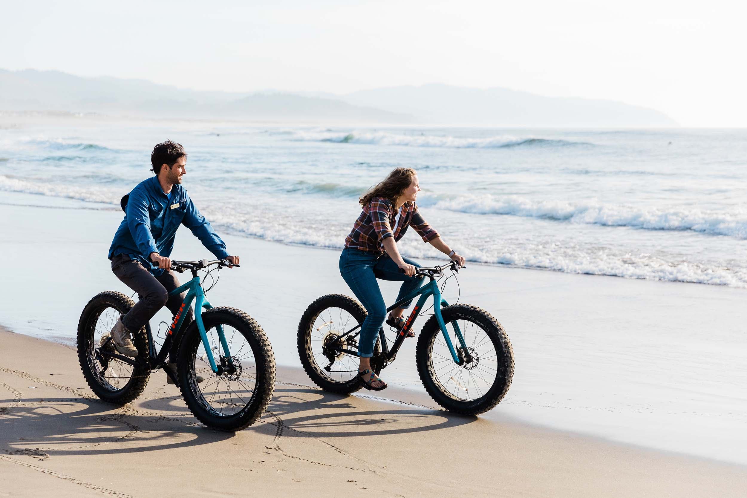 A couple riding bikes on the beach at Headlands