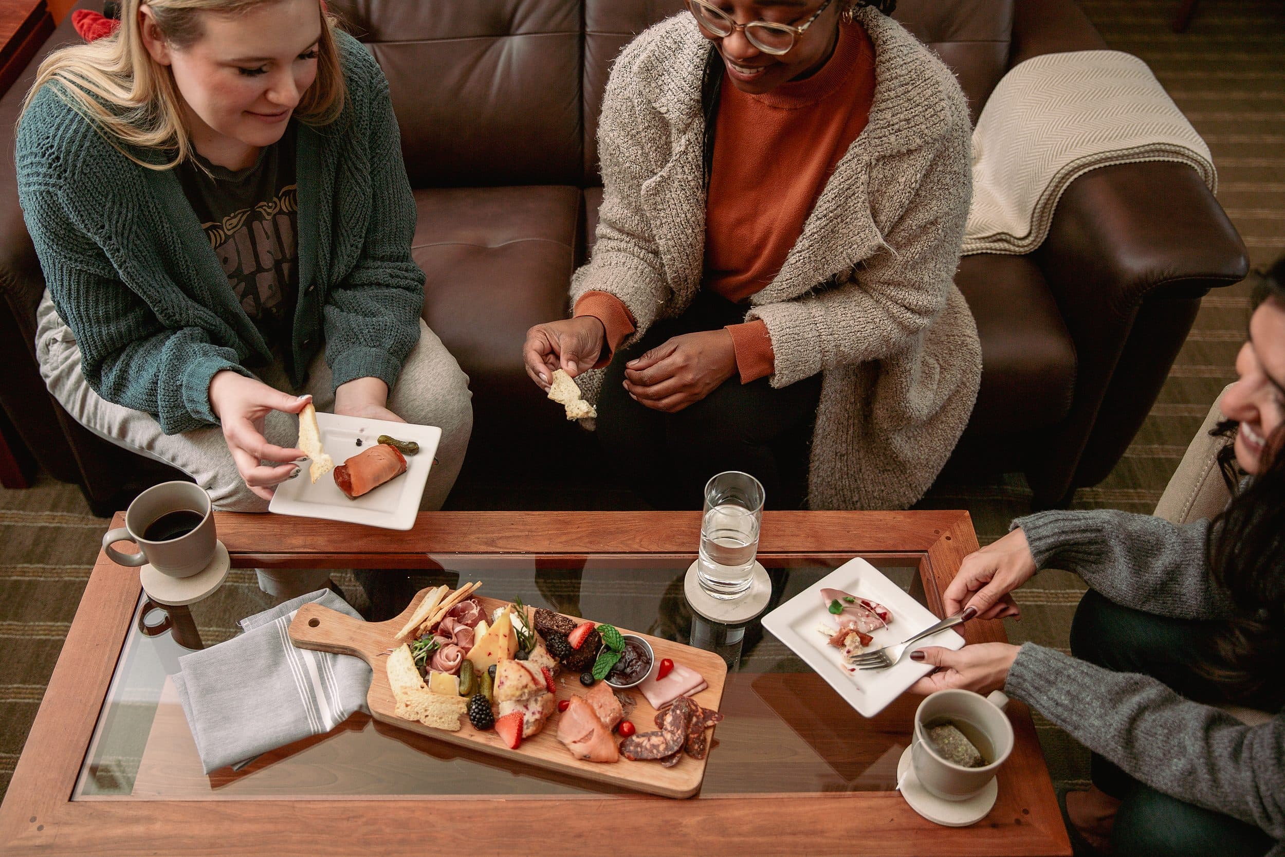 Friends sharing a charcuterie board and coffee in the cozy lounge at Headlands Coastal Lodge & Spa on the Oregon Coast