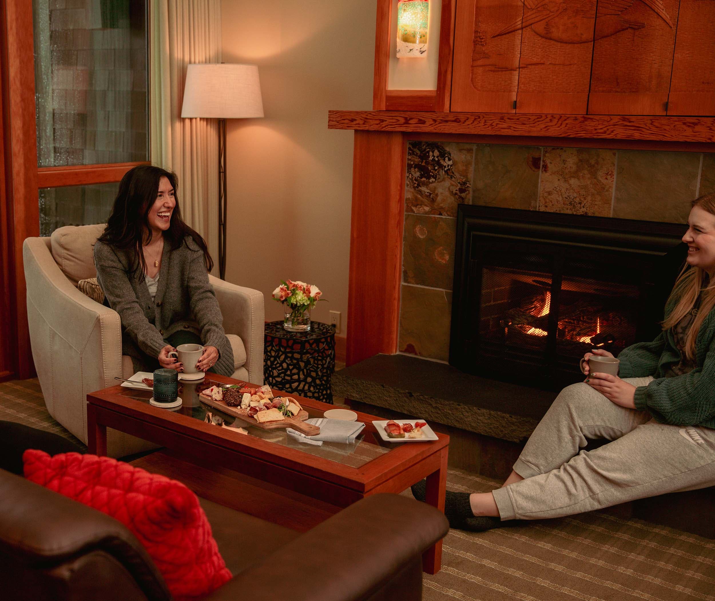 Two women laughing in the living space in a room at Headlands during girls weekend