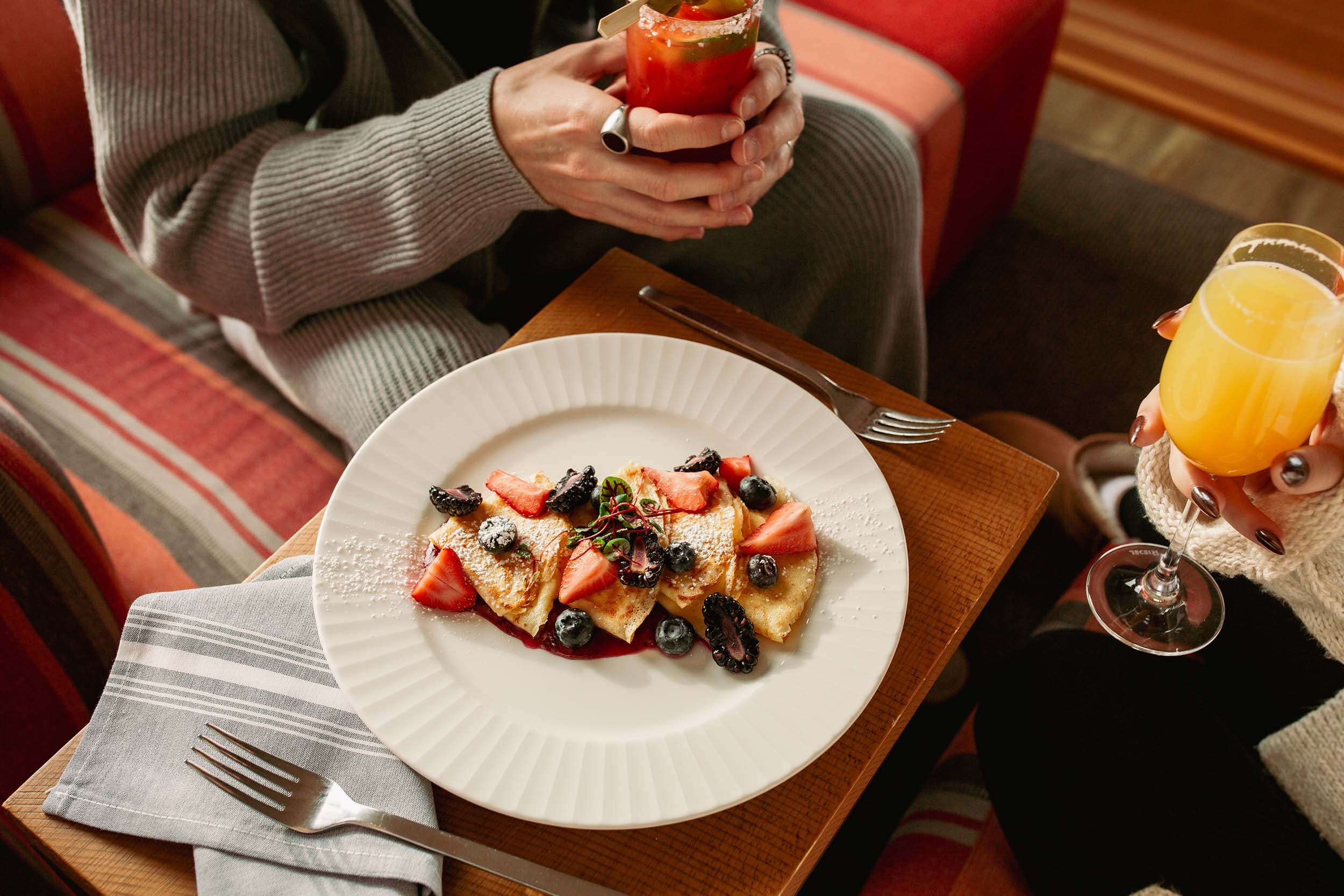 Two people charing a crepe breakfast at Headlands drinking brunch cocktails