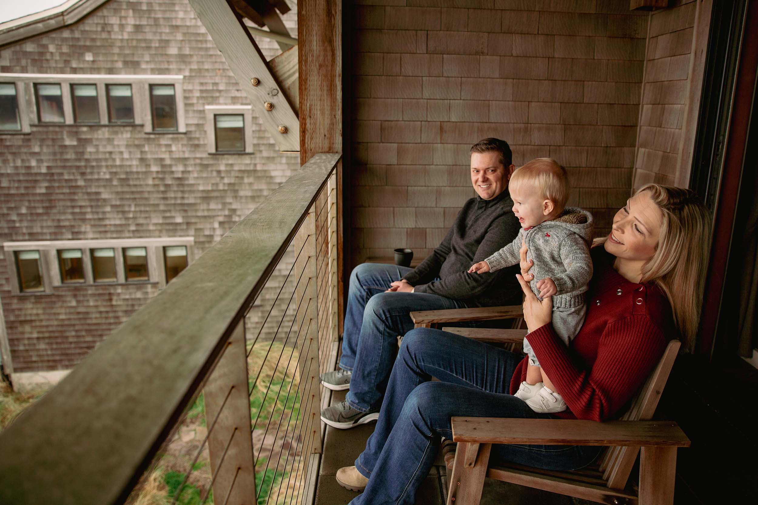 A family of 3 sitting on their room balcony at Headlands