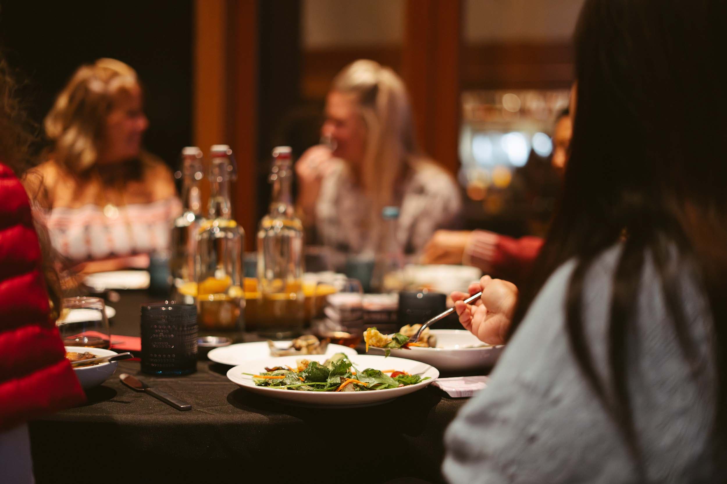 A group of people eating food and having a good time at the Fireside Room at Headlands