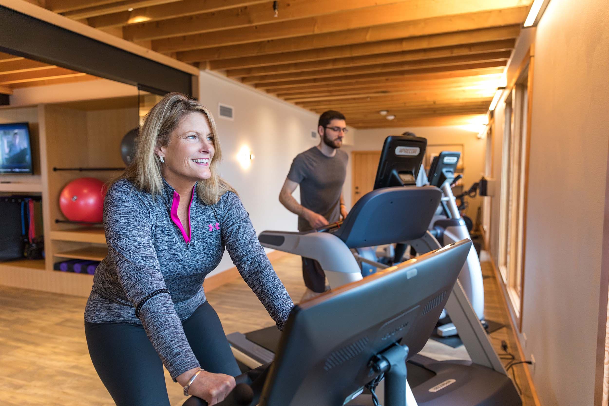 A woman on a fitness bike and a man on a treadmill in the fitness center at Headlands