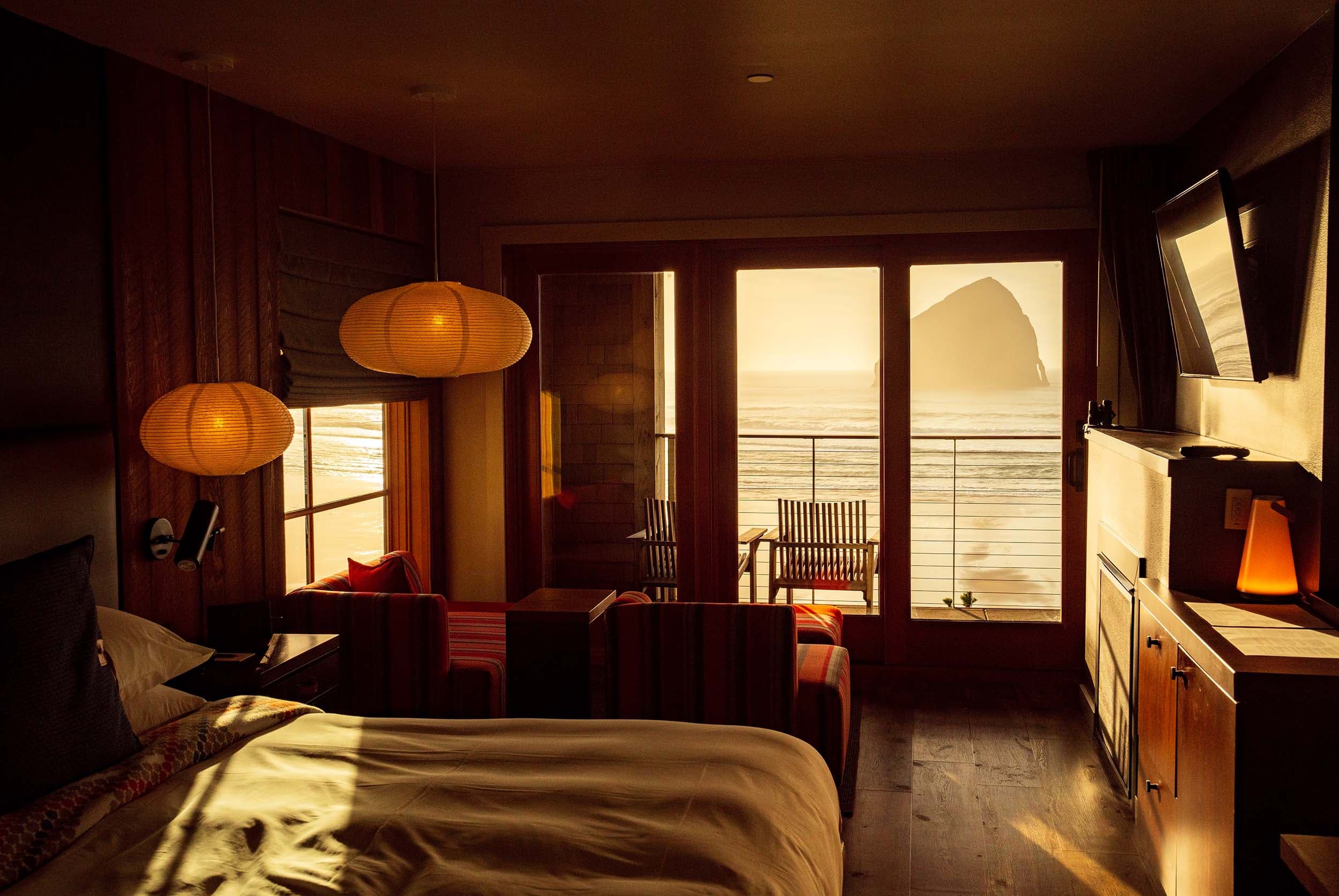 A room illuminated with golden light with a view of Haystack rock at Headlands