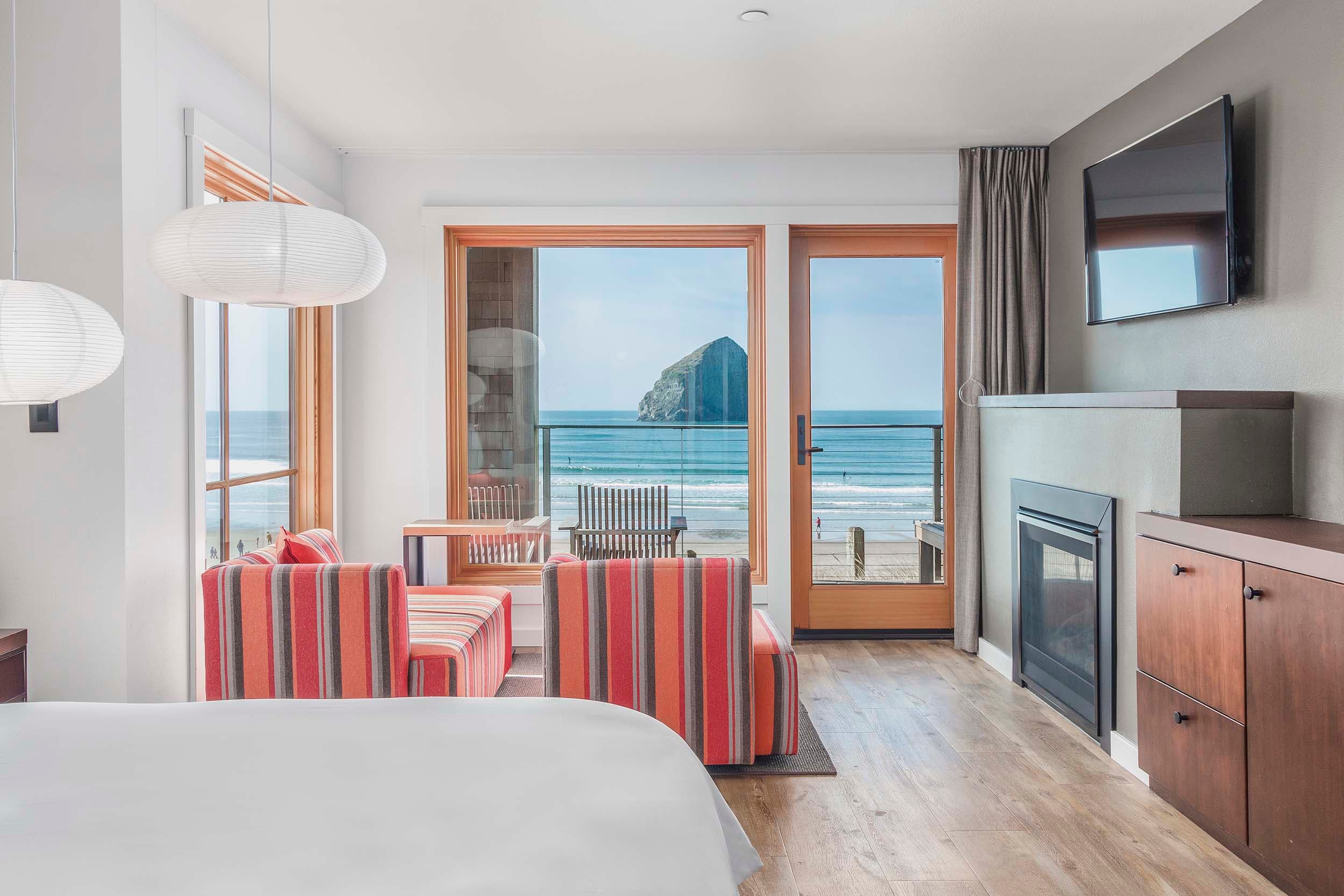 A sleeping area with a desk and lots of windows looking onto the beach and Haystack rock in a King Sunlight Accessible at Headlands