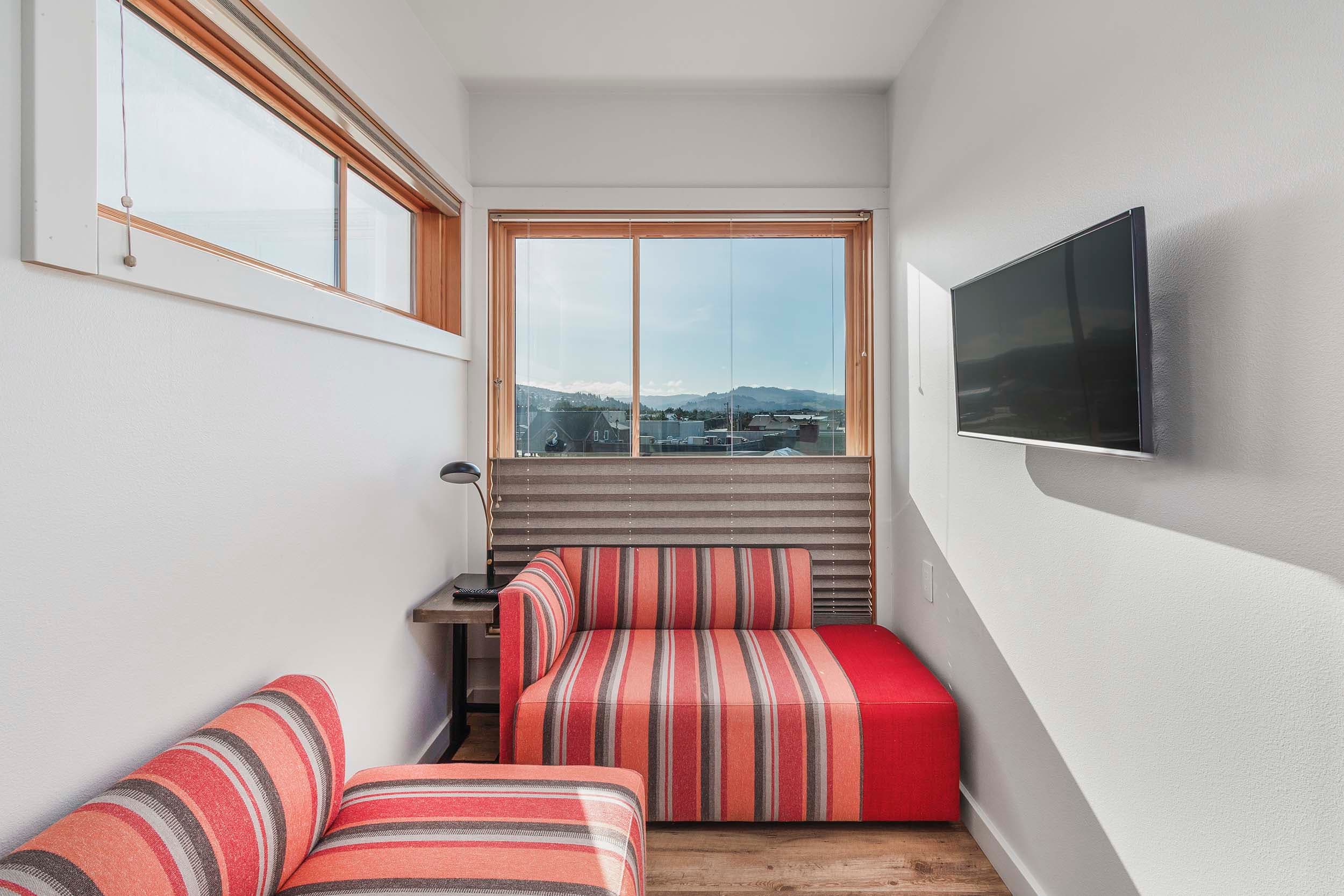A small lounge room with a TV and a window separate from the other room in a Corner King Sunlight Accessible at Headlands