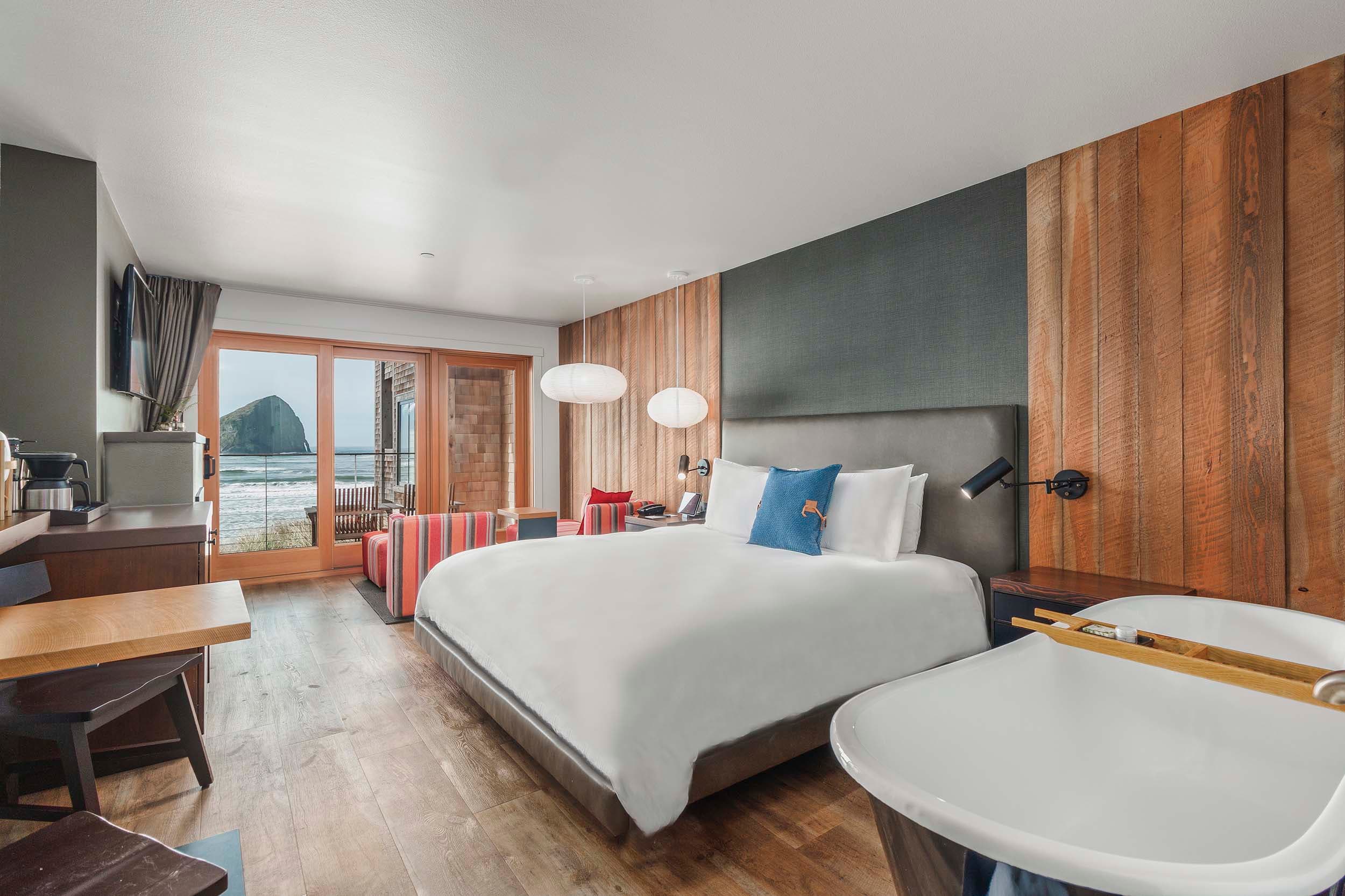 a bed, desk, tub, and lounge area in a King Signature room in the Oceanfront lodge at Headlands with a view of Haystack rock