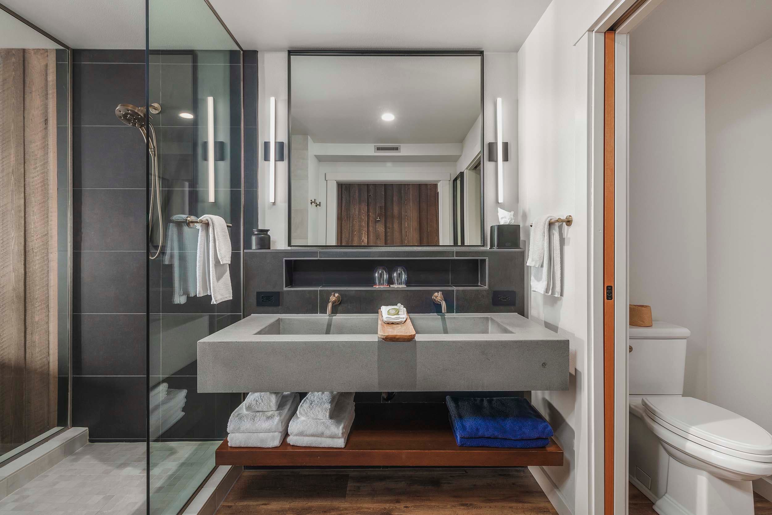 A modern bathroom with a glass shower and a concrete sink in a King Signature room in the Oceanfront lodge at Headlands