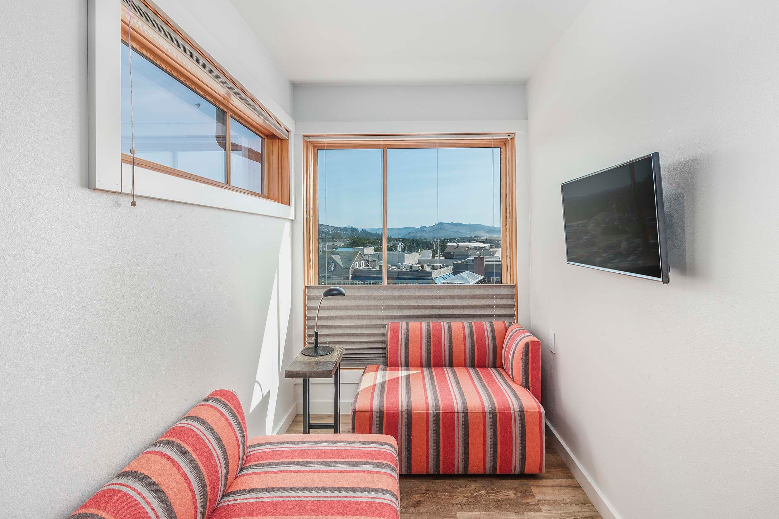 A small lounge room with a TV and a window separate from the other room in a Corner King Sunlight Top Floor at Headlands