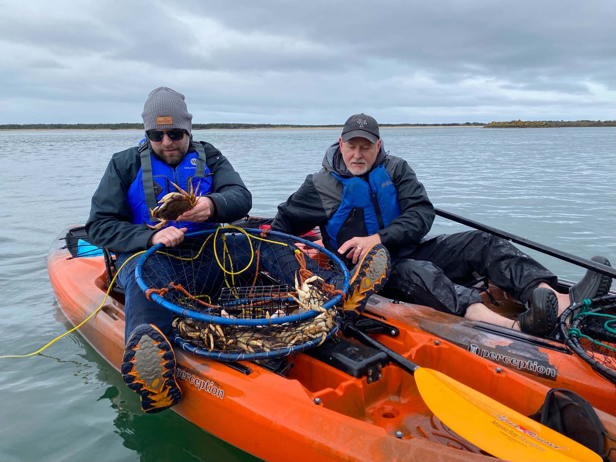 Two men in kayaks fishing for crabs near Headlands