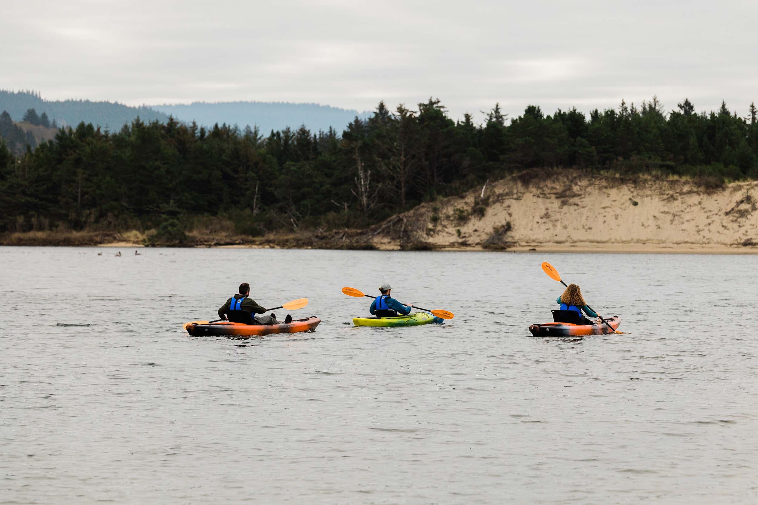 3 people in the water kayaking close to the shore