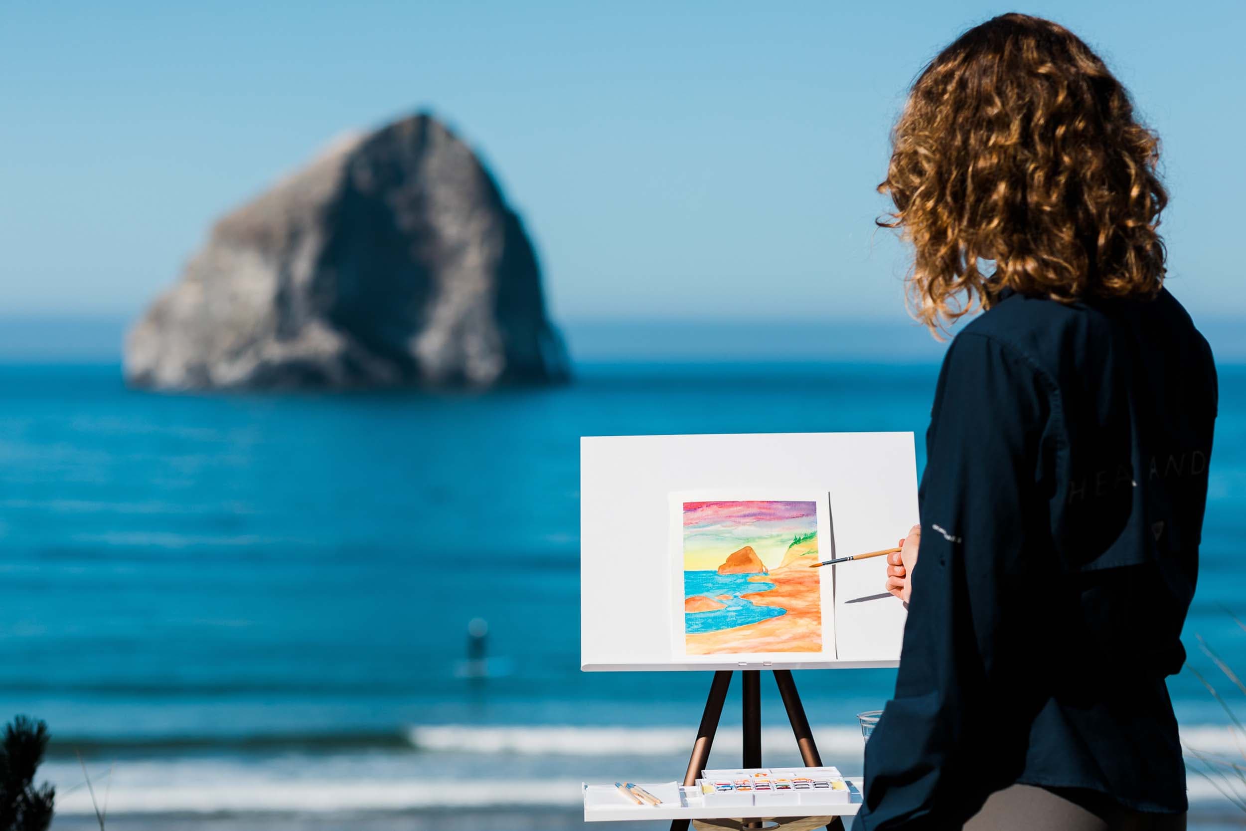 A woman painting using water colors on the beach