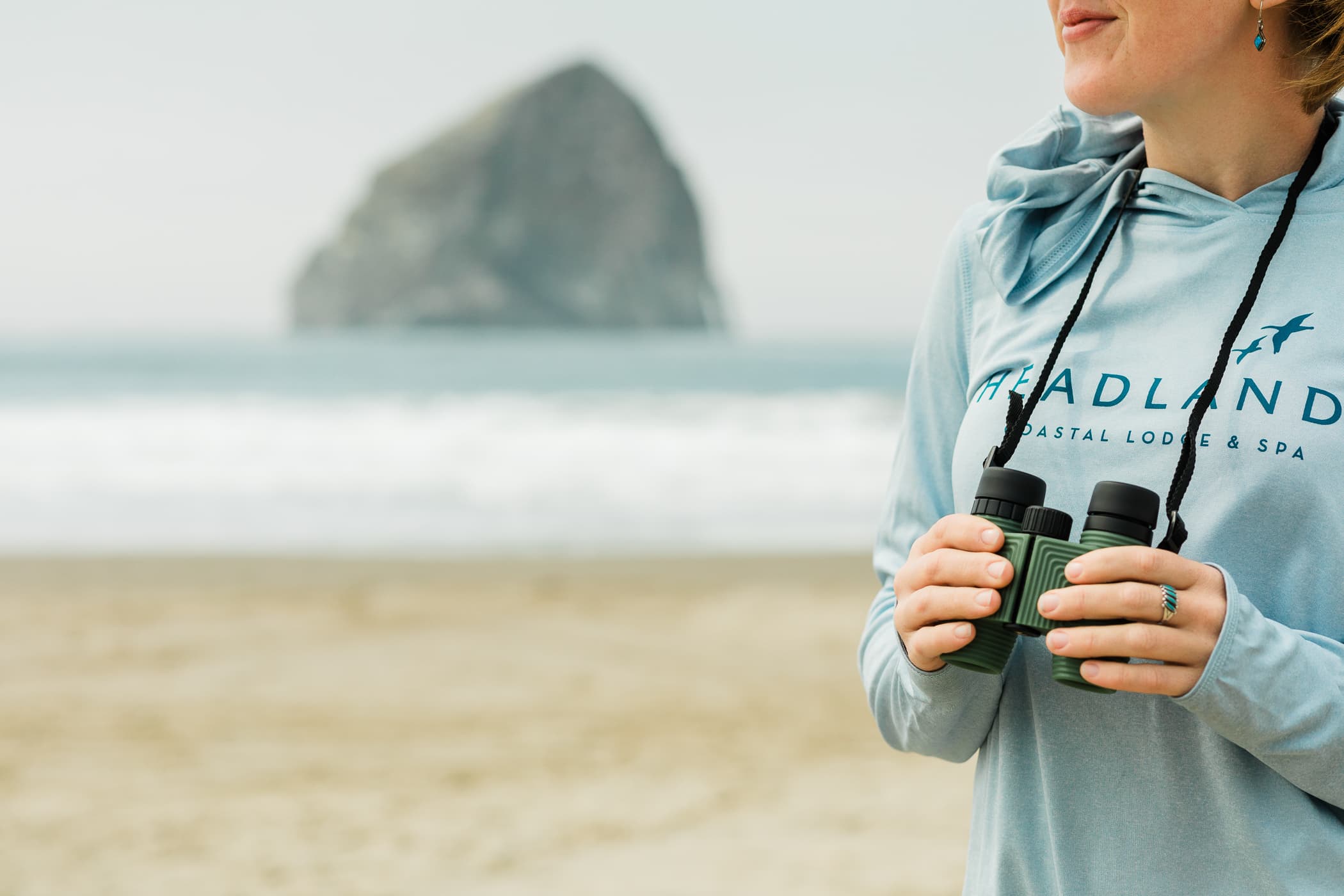 A woman on the beach holding binoculars