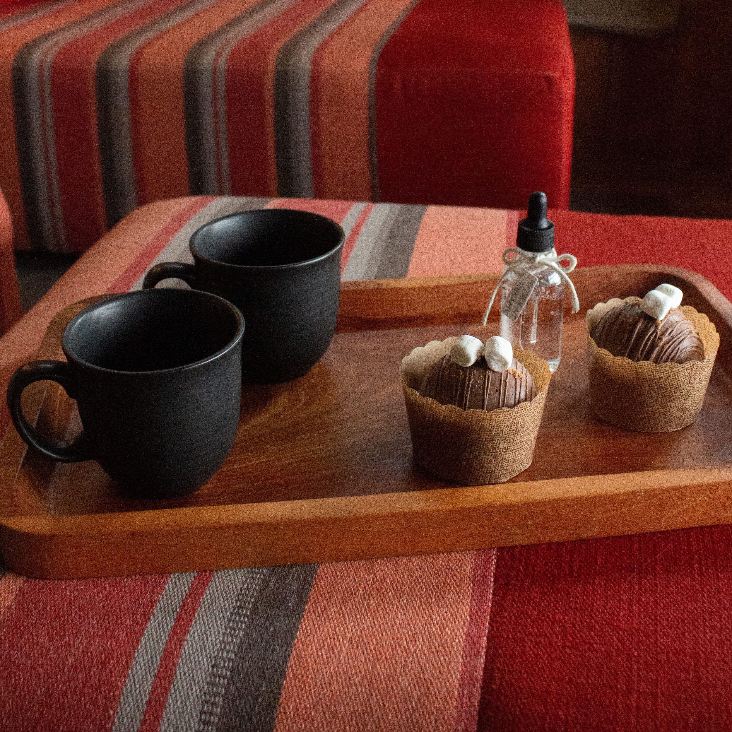 Some Christmas sweets on a serving tray with two black mugs at Headlands