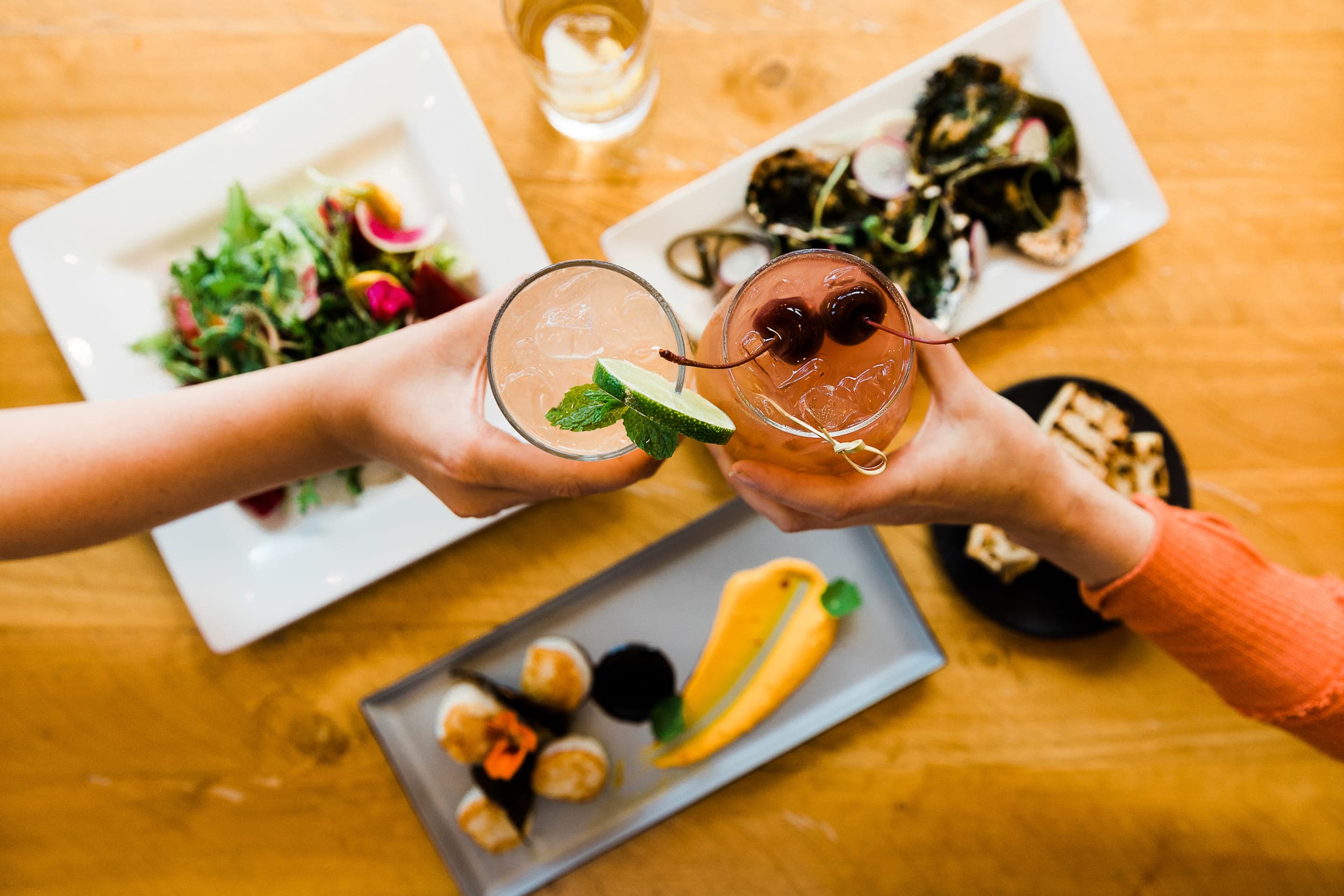 An assortment of sharable food and 2 cocktails at Meridian Restaurant & Bar